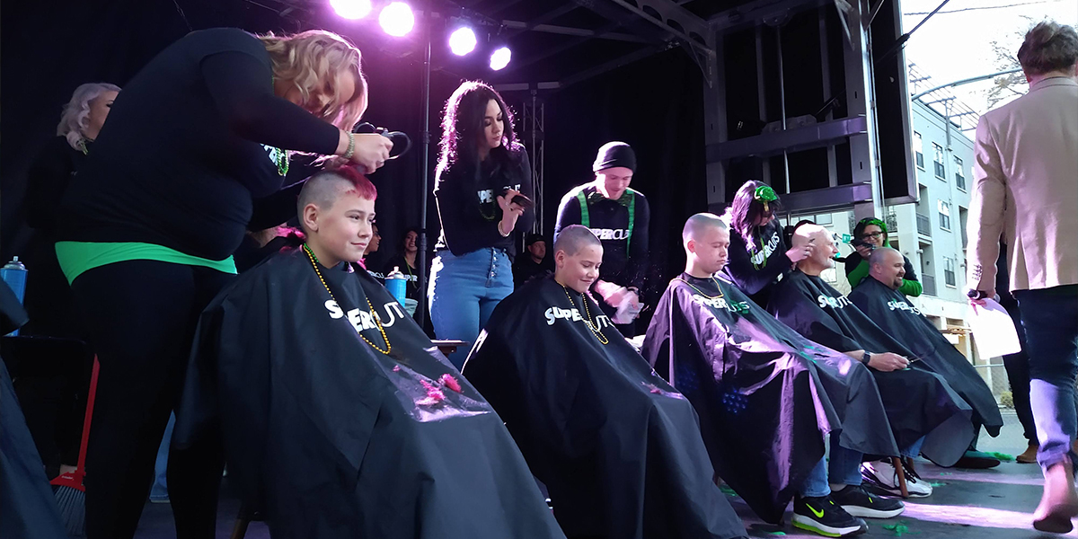 Boys and men getting their hair shaved on stage.